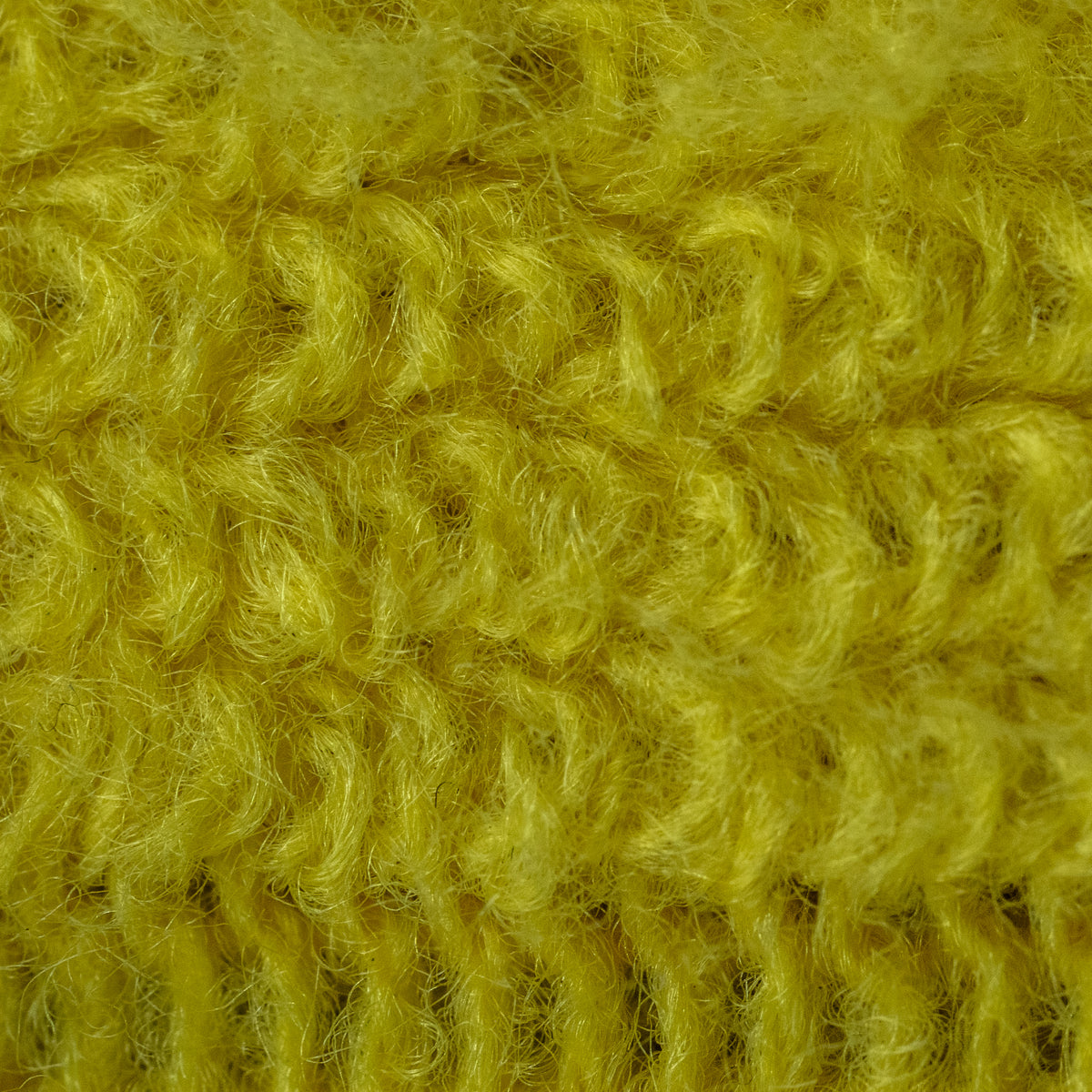 A close-up texture shot of a fuzzy, chunky knit fabric in a vibrant mustard yellow color.