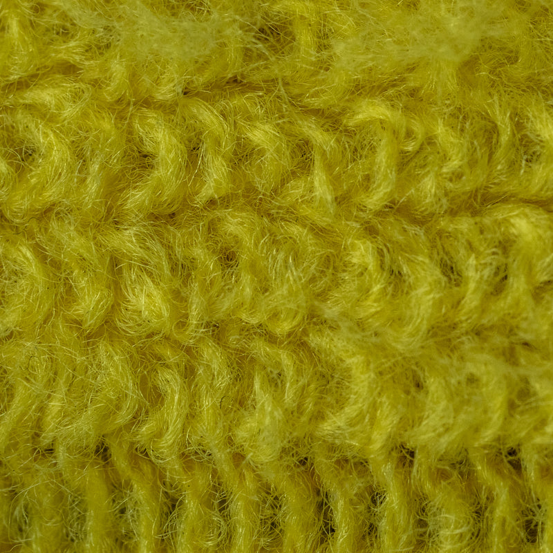A close-up texture shot of a fuzzy, chunky knit fabric in a vibrant mustard yellow color.