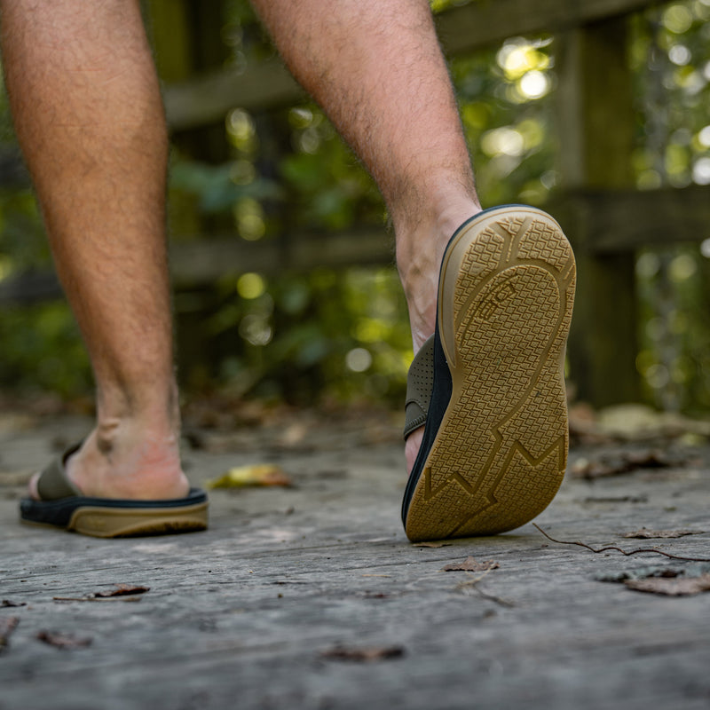 Deep Moss Flights sandal molded EVA outsole close-up mid-step on a wooden boardwalk
